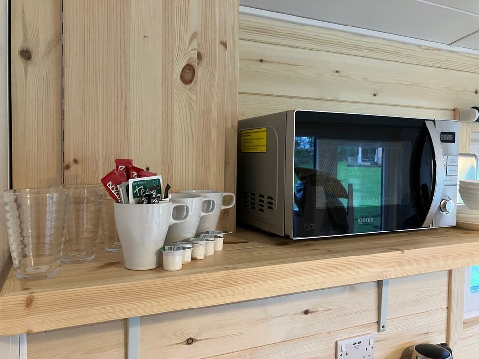 A kitchen area with a microwave and cups at Sherwood - Family Pod 3 in Mansfield