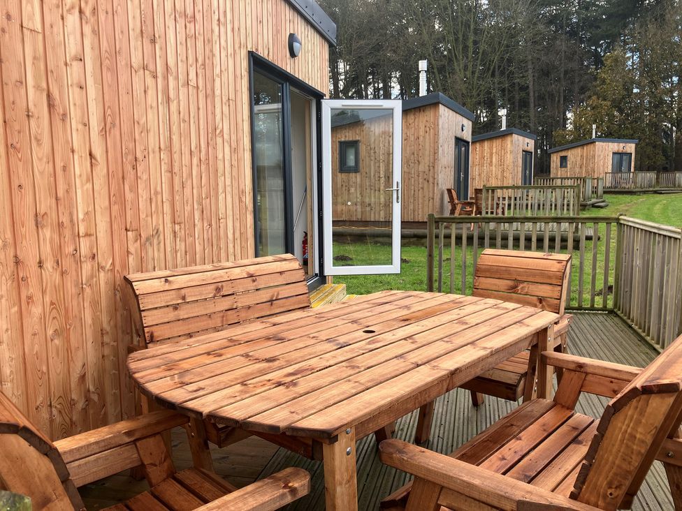 An outdoor seating area with a wooden table and chairs at Sherwood - Family Pod 3 in Mansfield