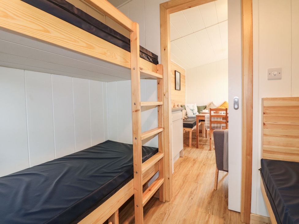 A bedroom with bunk beds and a doorway leading to another room at Sherwood Pines - Family Pod 3 near Edwinstowe