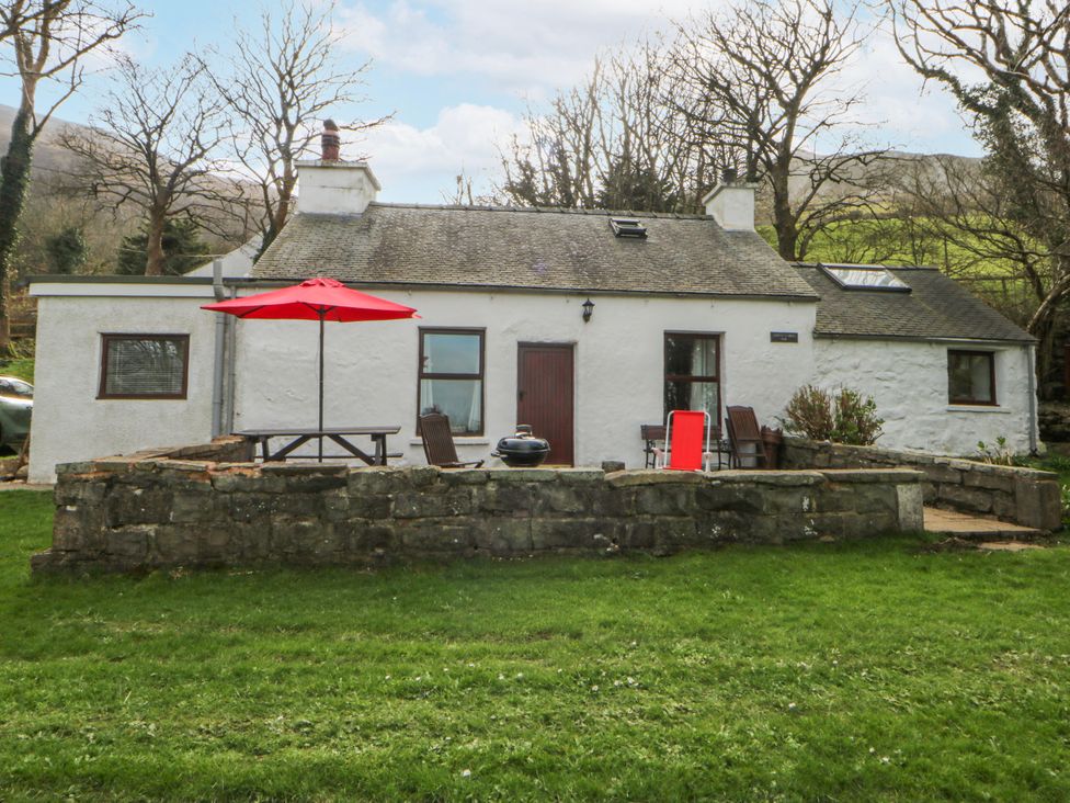 An outdoor area with a cottage and seating at Llwyn Y Brig Isaf in Caernarfon