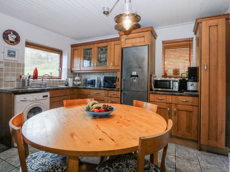 A kitchen with a wooden table and appliances at Llwyn Y Brig Isaf in Caernarfon