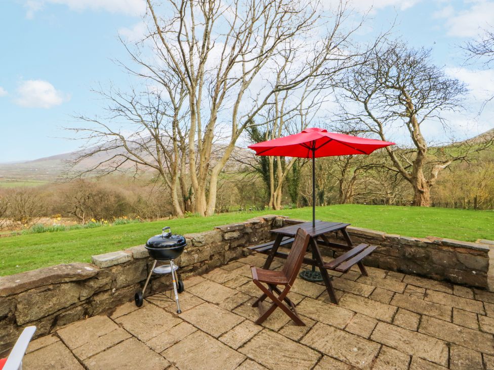 An outdoor seating area with a red umbrella and grill at Llwyn Y Brig Isaf in Caernarfon