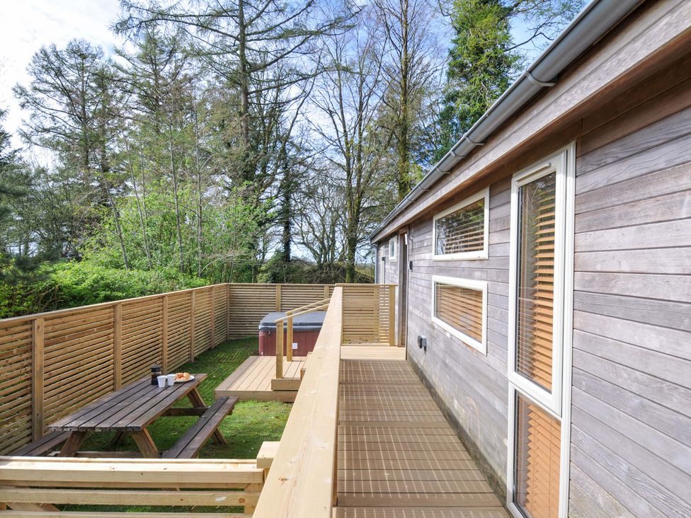 An outdoor deck area with a table and hot tub at 3 Faraway Fields in Dobwalls