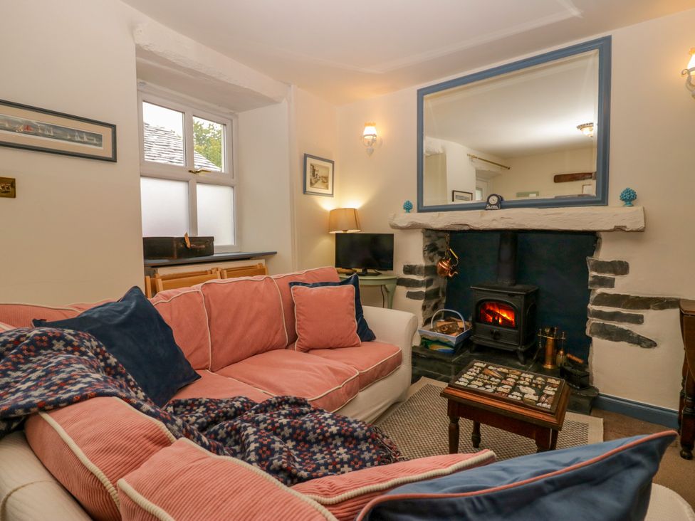 A living room with a sofa and fireplace at Corner Cottage in Lowick Green near Ulverston