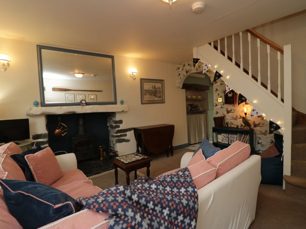A living room with a fireplace and sofa at Corner Cottage in Lowick Green near Ulverston