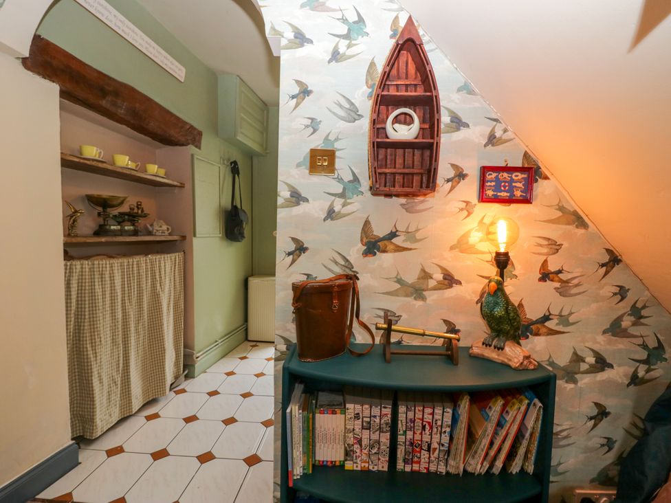 A kitchen area with a bookshelf and light fixture at Corner Cottage Lowick Green near Ulverston