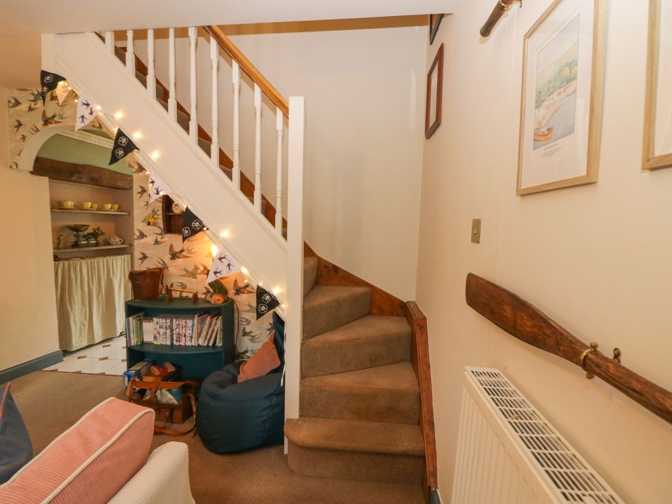 A hallway with a staircase and shelves at Corner Cottage in Lowick Green near Ulverston
