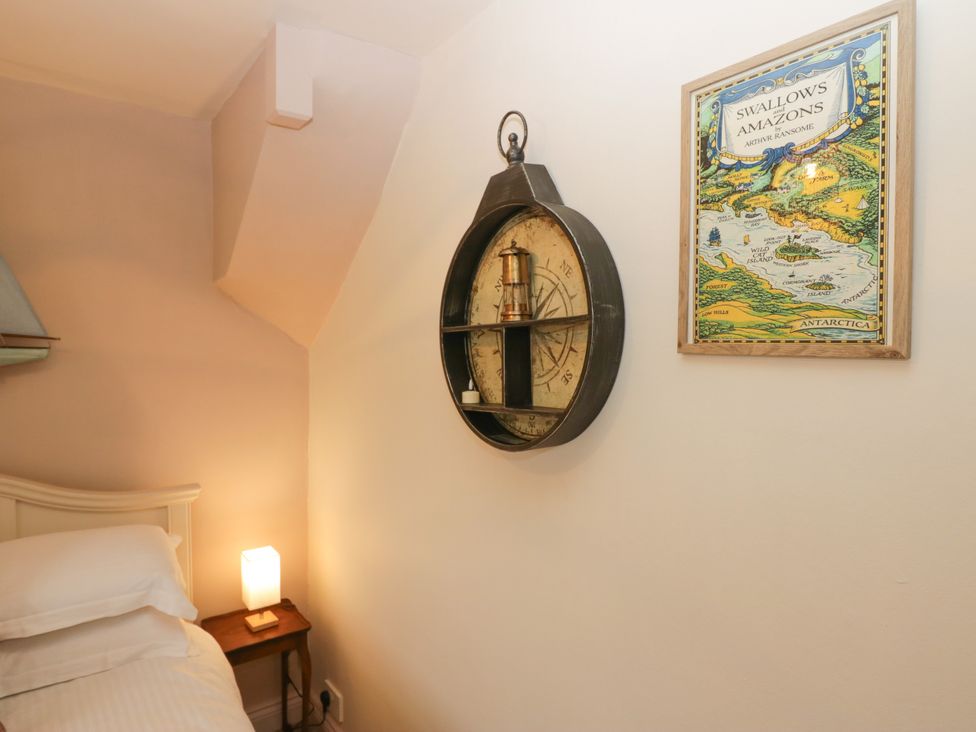 A bedroom featuring a bed, bedside lamp, and wall clock at Corner Cottage Lowick Green near Ulverston