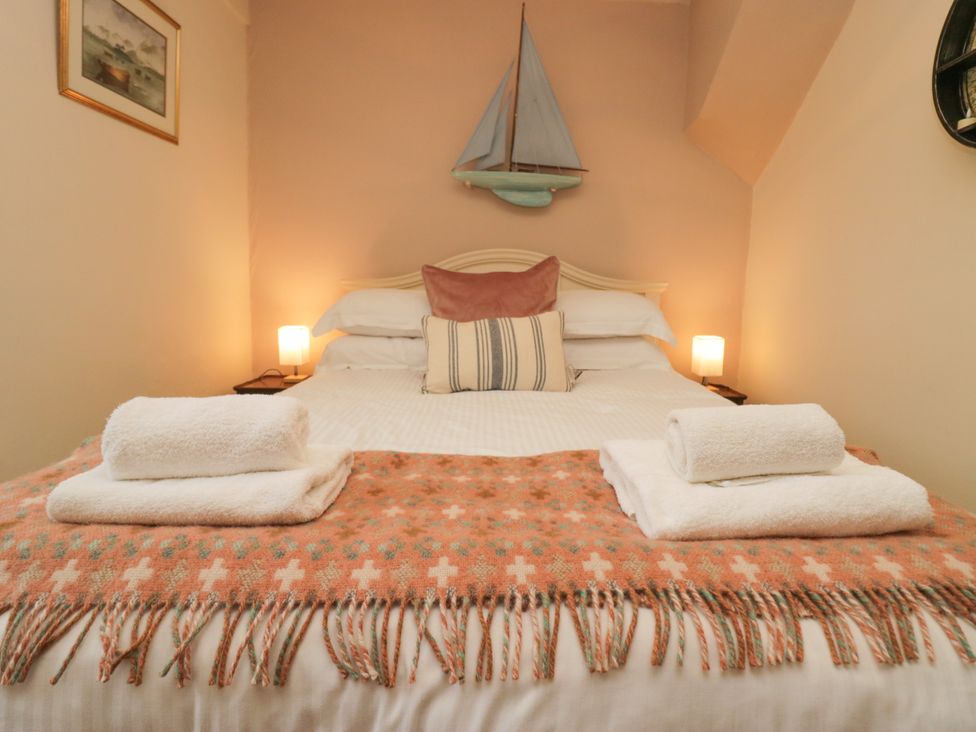 A bedroom with a bed and decorative items at Corner Cottage Lowick Green near Ulverston