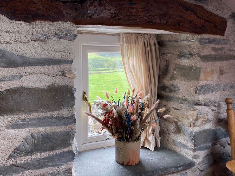 A window with curtains and a vase of dried flowers at Corner Cottage in Lowick Green near Ulverston