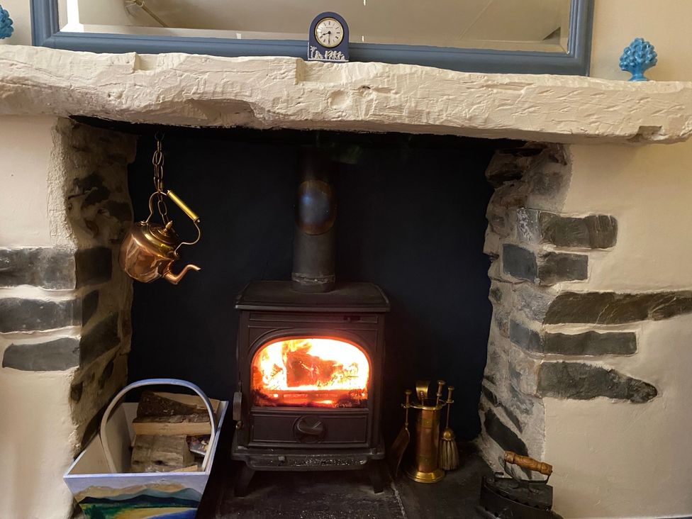 A living room with a wood stove and kettle at Corner Cottage in Lowick Green near Ulverston