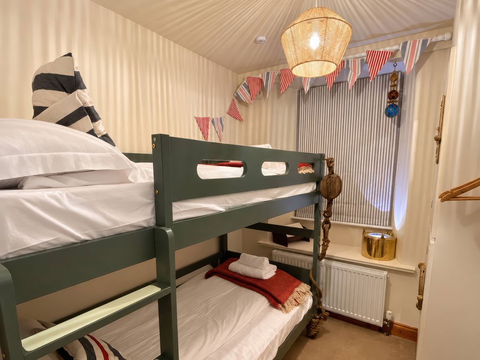 A bedroom with a bunk bed and decorative bunting at Corner Cottage Lowick Green near Ulverston
