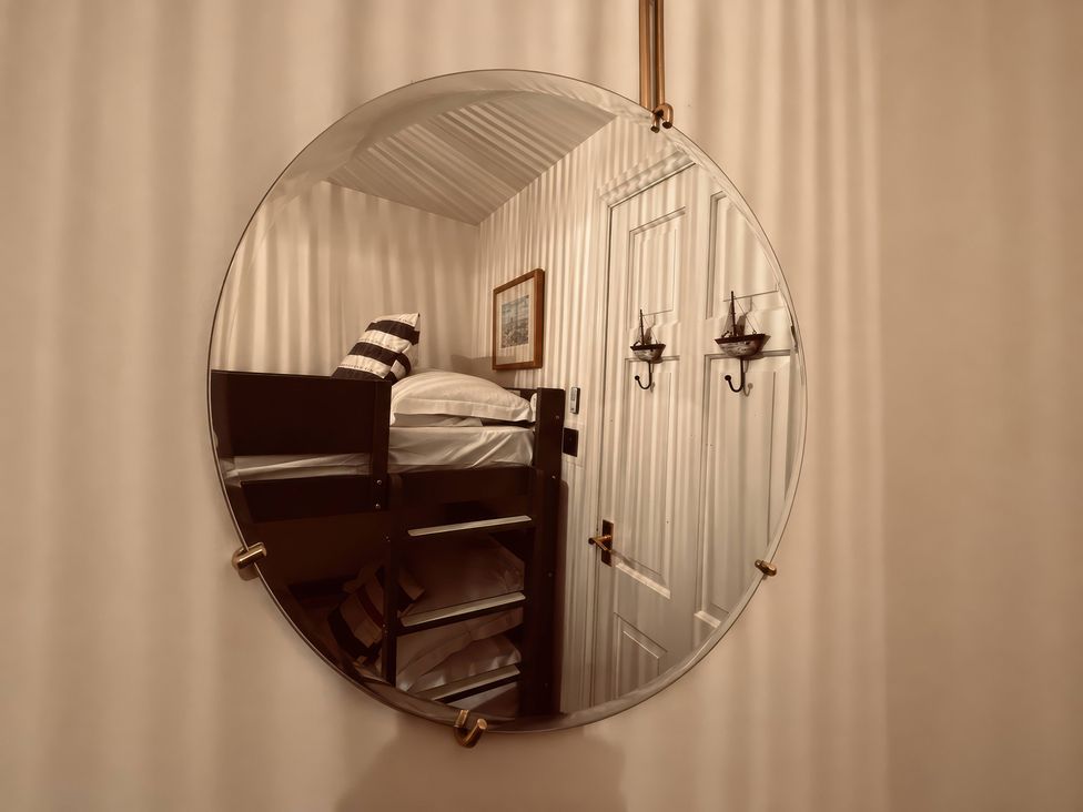 A mirror reflecting a bed and door at Corner Cottage in Lowick Green near Ulverston