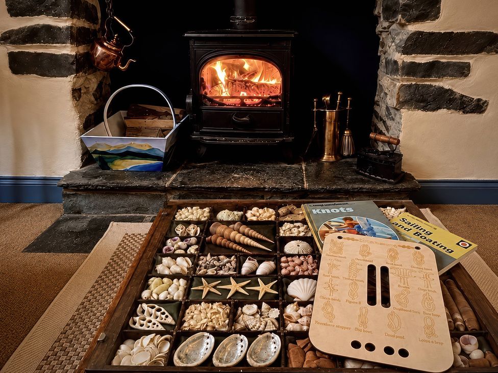 A living room with a wood stove and decorative shells at Corner Cottage in Lowick Green near Ulverston