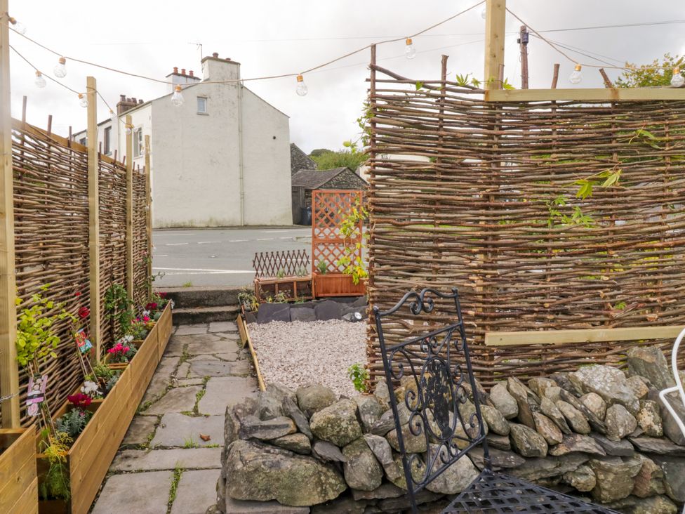A garden with a stone wall and gravel area at Corner Cottage in Lowick Green near Ulverston