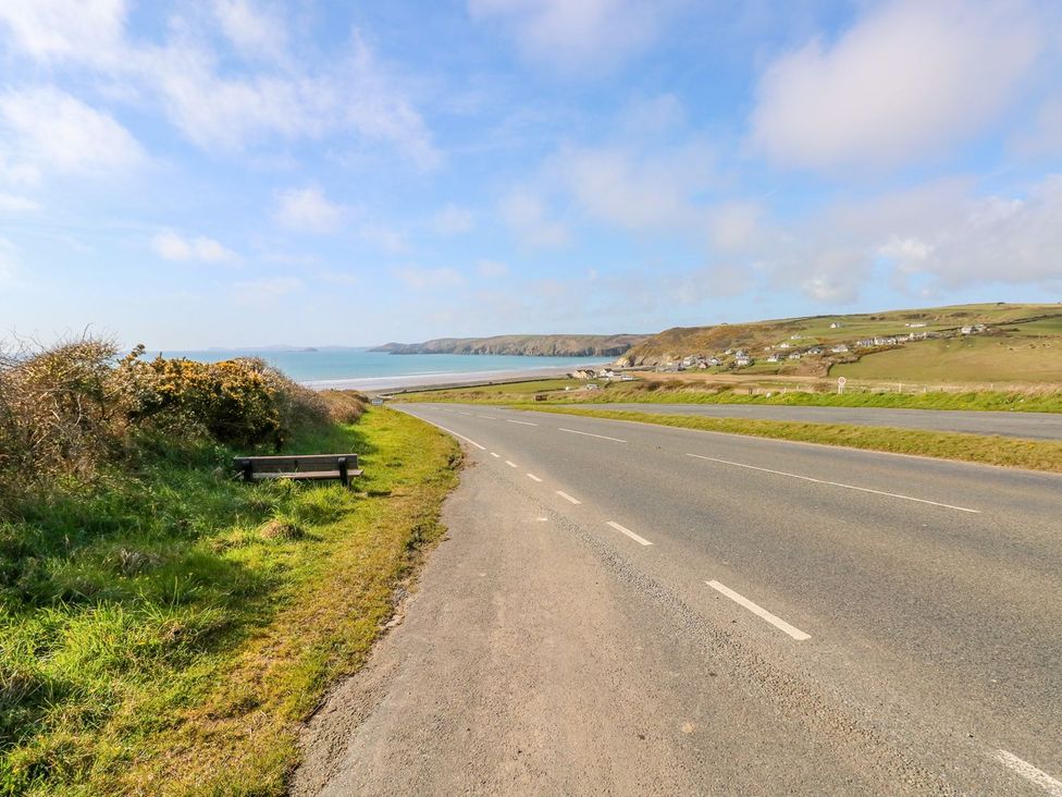 A road with a bench and ocean view at Park Hall Cottage in Solva