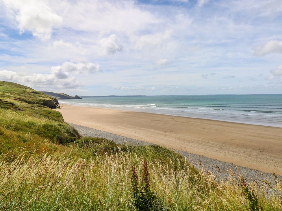 A beach with grass in the foreground at Park Hall Cottage in Solva