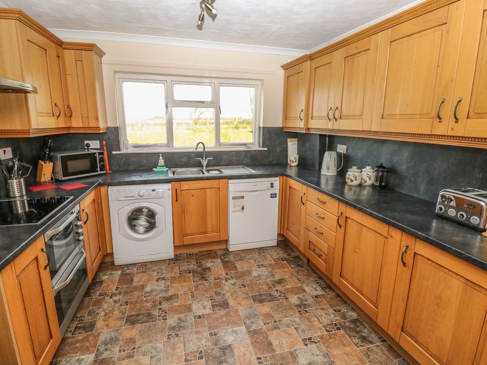 A kitchen with cabinets, sink, washing machine, and dishwasher at Maerdy Lodge