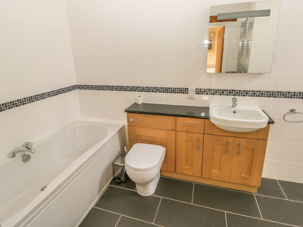 A bathroom with a bathtub, toilet, sink, and cabinet at Maerdy Lodge