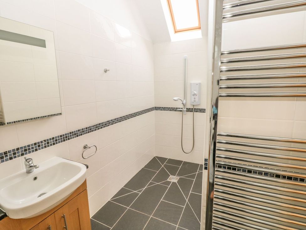 A bathroom with a sink, mirror, shower, and towel rack at Maerdy Lodge