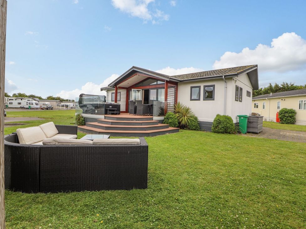 A garden area with a sofa and a house at Honeysuckle Lodge in Towyn