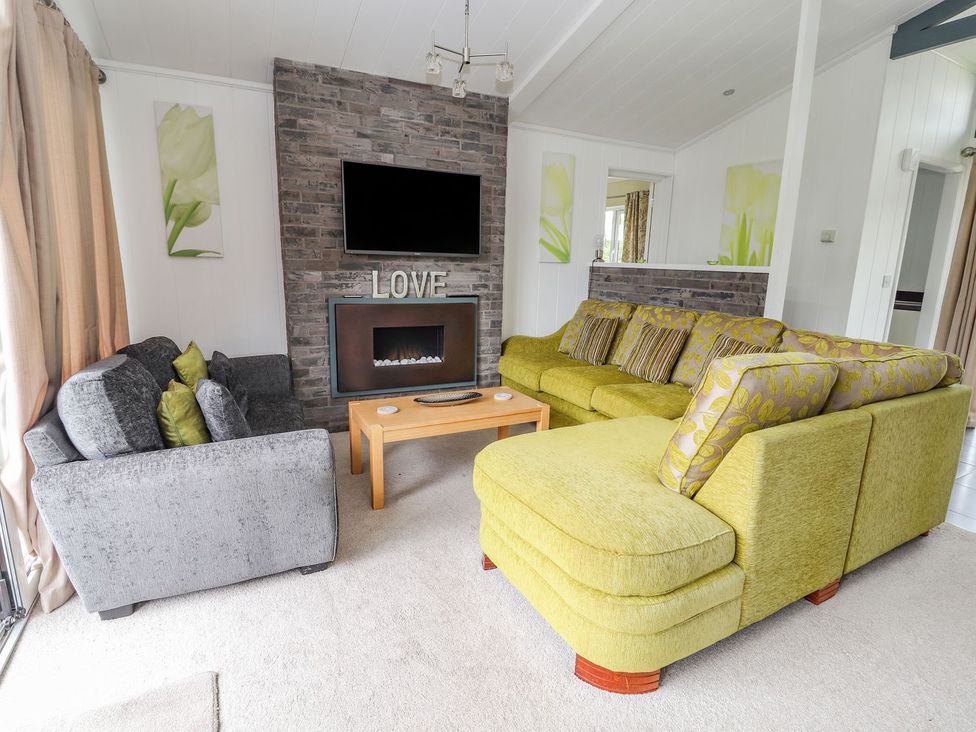 A living room with a sofa and armchair at Honeysuckle Lodge in Towyn