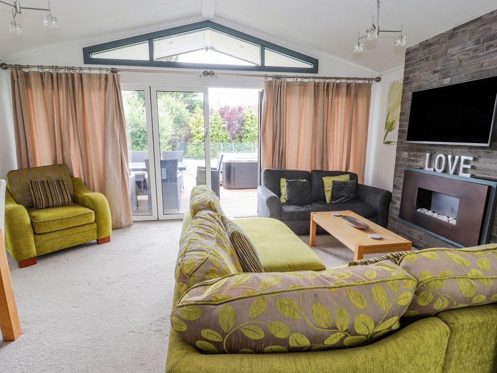 A living room with a sofa and an armchair at Honeysuckle Lodge Towyn