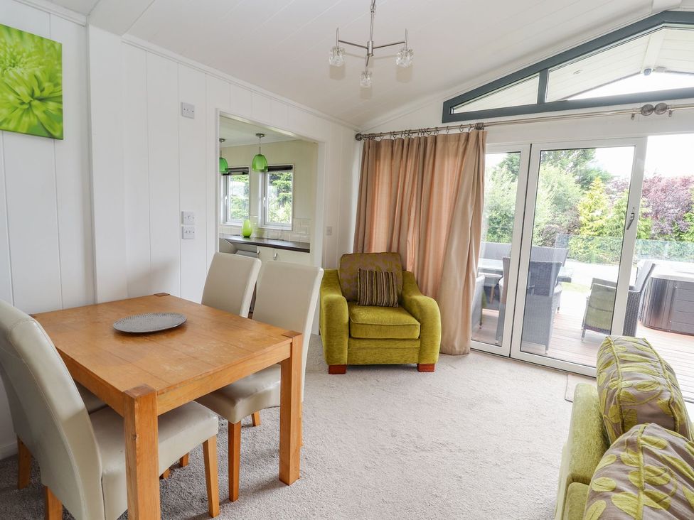 A living room with a table and chairs at Honeysuckle Lodge in Towyn