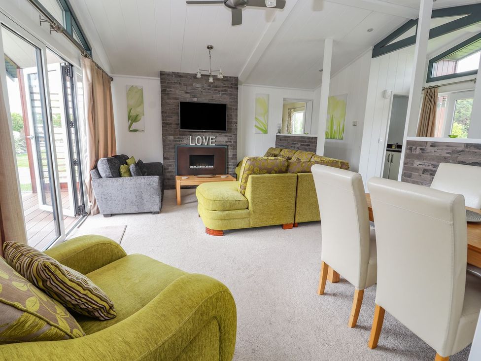 A living room with sofas and a dining table at Honeysuckle Lodge Towyn