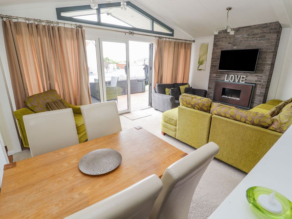 A living room with a sofa and table at Honeysuckle Lodge in Towyn