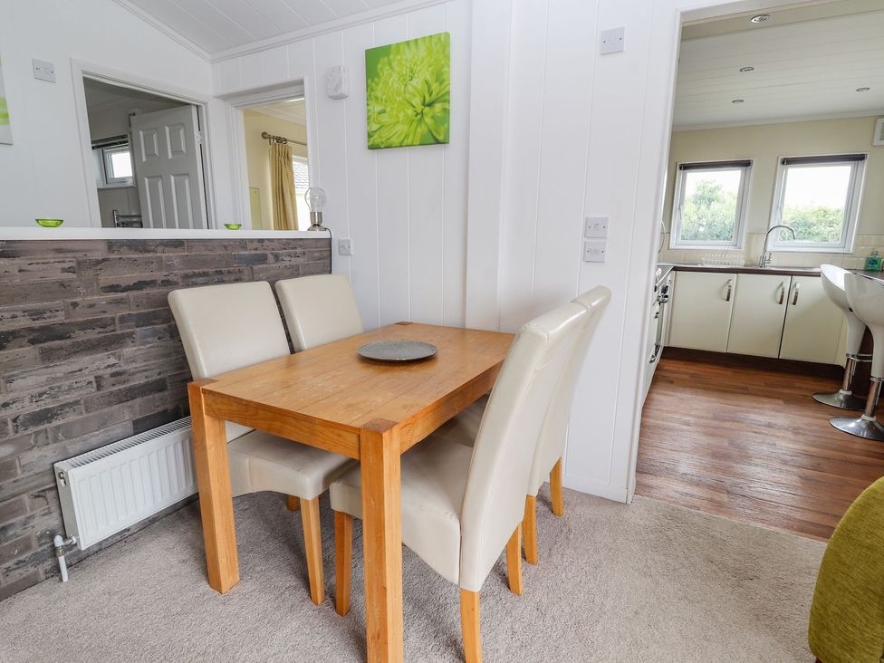 A dining area with a table and chairs at Honeysuckle Lodge in Towyn