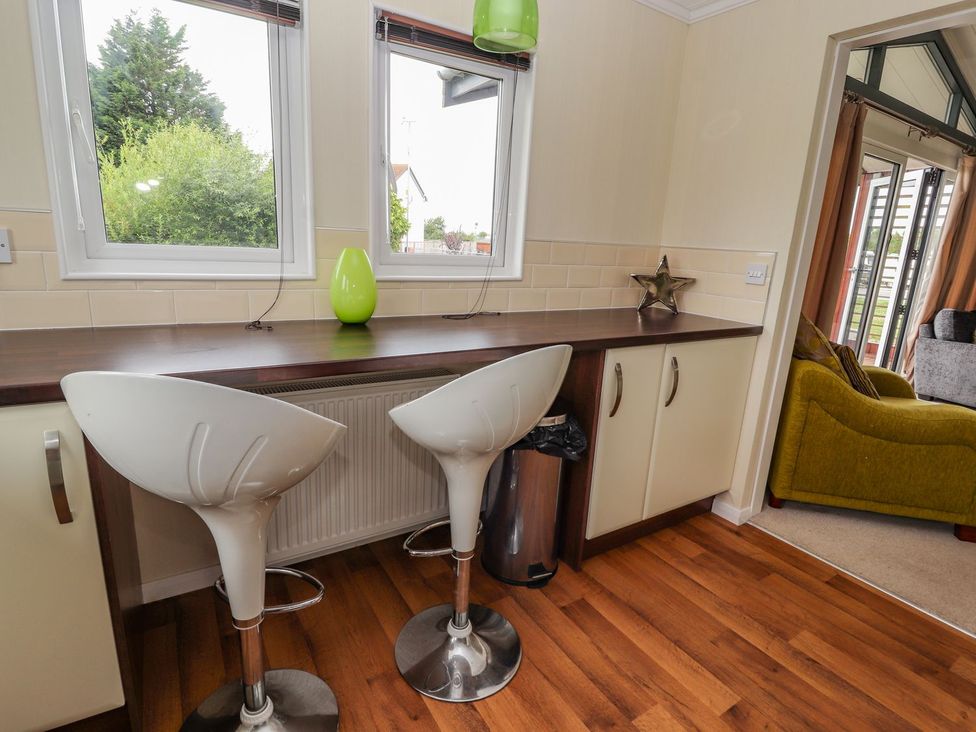 A kitchen with bar stools and a countertop at Honeysuckle Lodge in Towyn