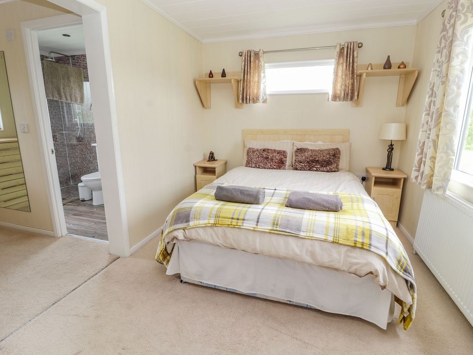 A bedroom with a double bed and attached bathroom at Honeysuckle Lodge Towyn