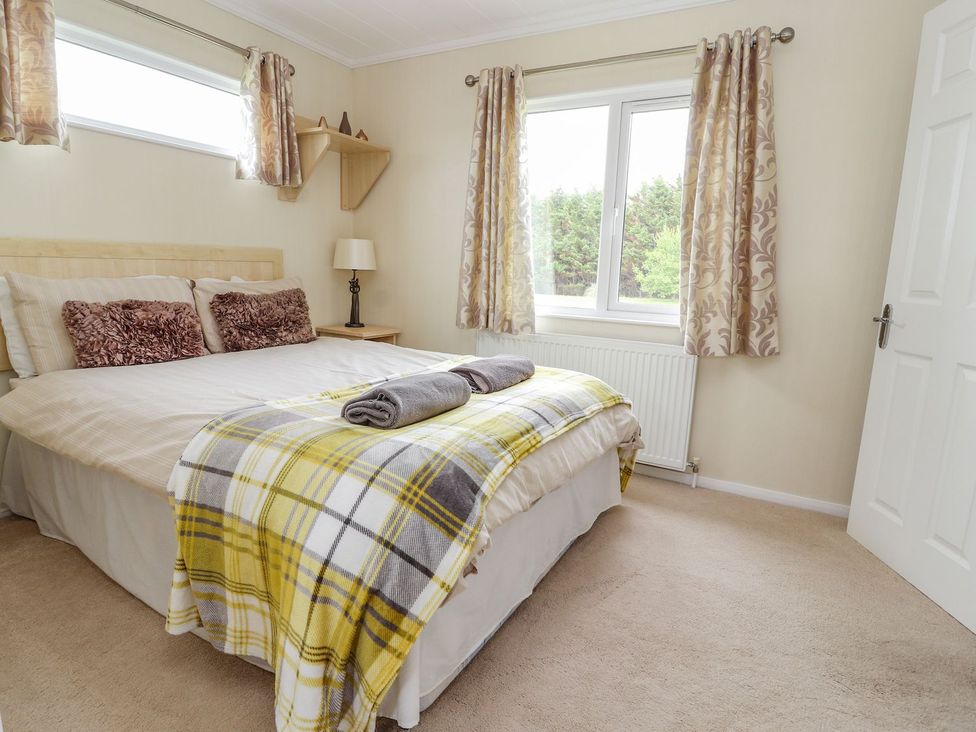 A bedroom with a bed and lamp at Honeysuckle Lodge in Towyn