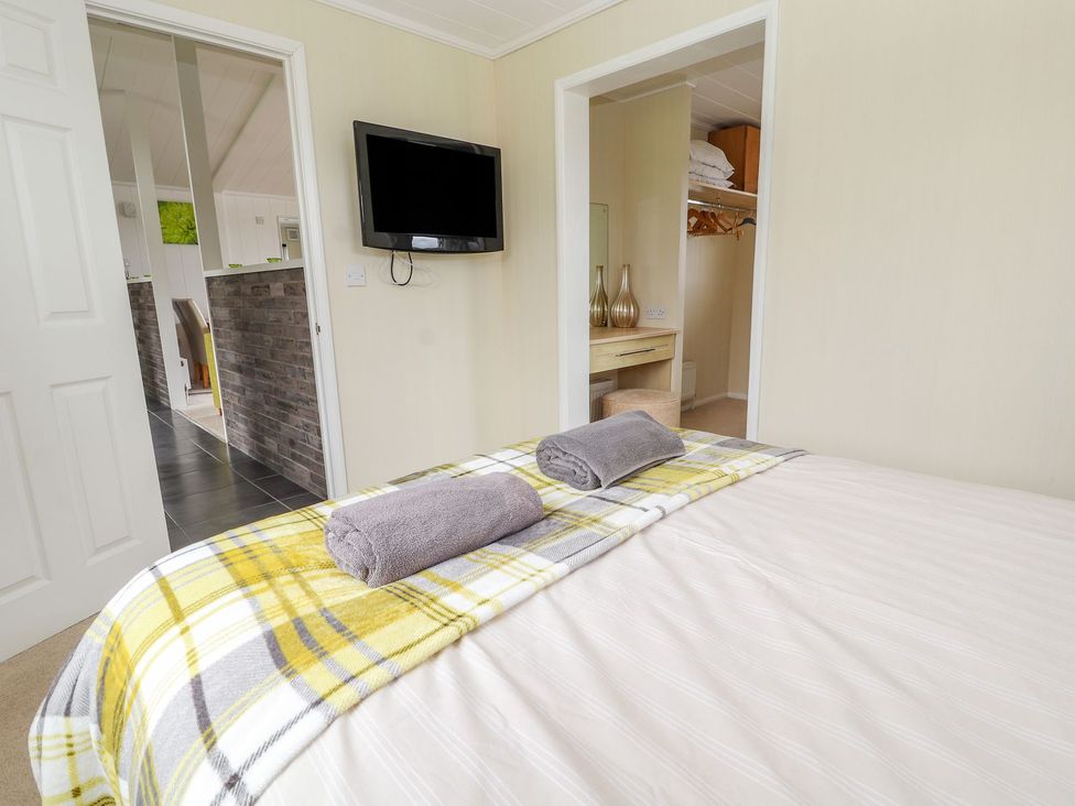 A bedroom with a bed and television at Honeysuckle Lodge Towyn