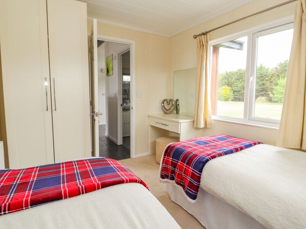 A bedroom with twin beds and a dressing table at Honeysuckle Lodge in Towyn