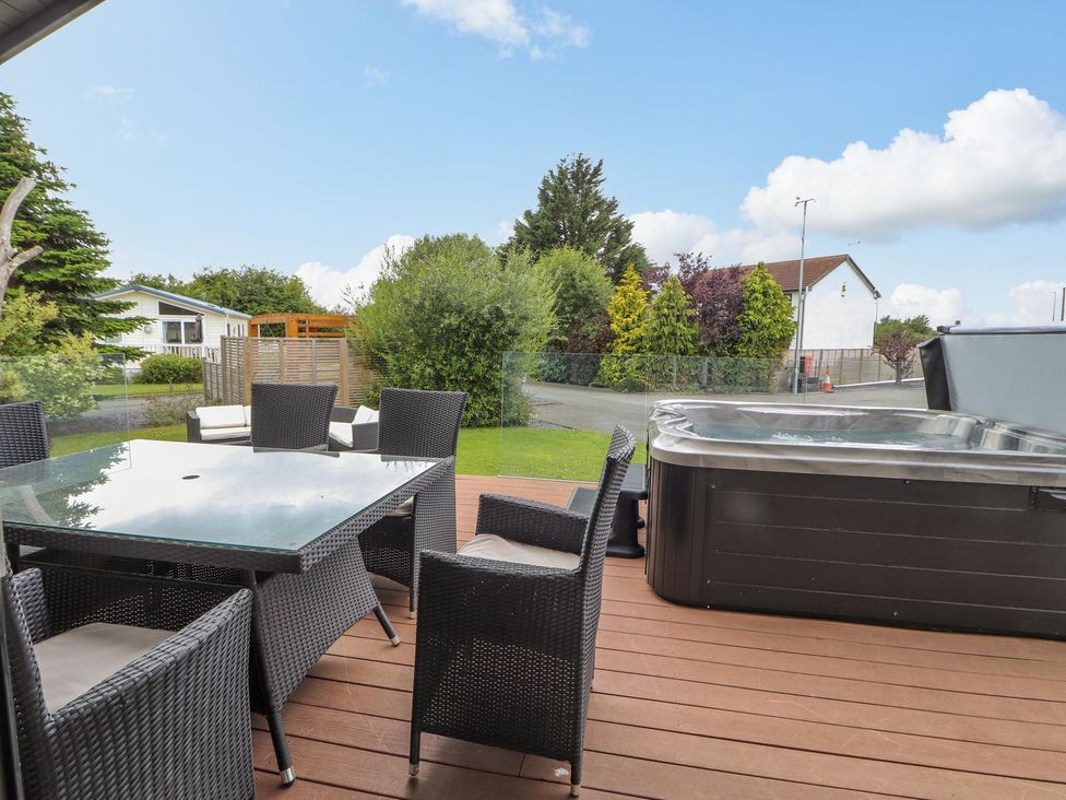 An outdoor area with a hot tub and seating at Honeysuckle Lodge in Towyn