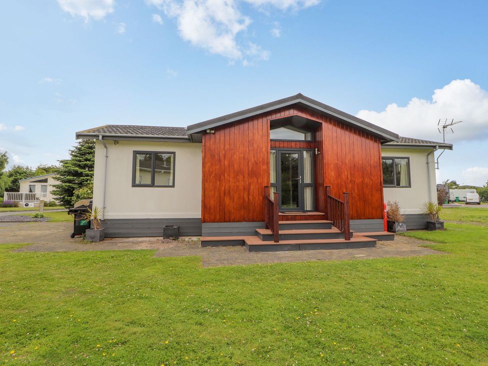 A house with wooden features and steps at Honeysuckle Lodge Towyn