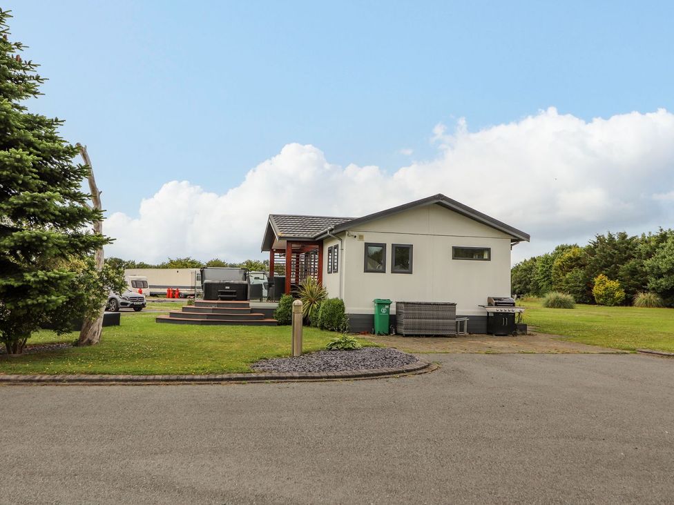A house with a deck and garden at Honeysuckle Lodge in Towyn