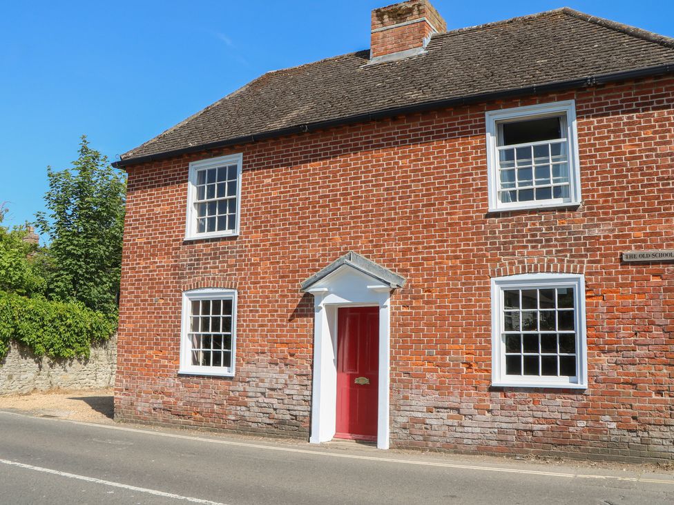 A house with a red door and multiple windows at The Old School House in Chichester