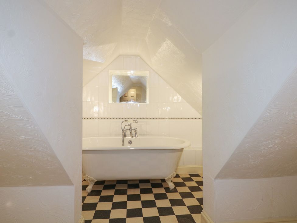 A bathroom with a bathtub and mirror at The Old School House in Chichester