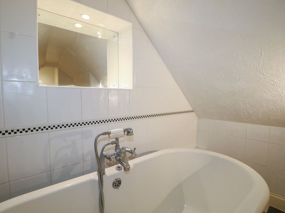 A bathroom with a bathtub and a mirror at The Old School House in Chichester