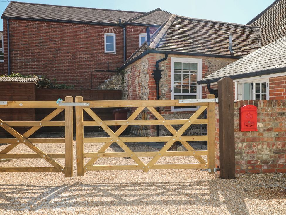 A wooden gate with a red mailbox and brick wall at The Old School House in Chichester