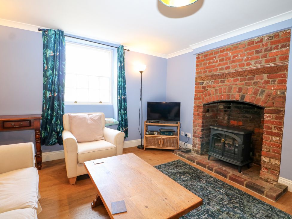 A living room with a sofa, table, and fireplace at The Old School House in Selsey