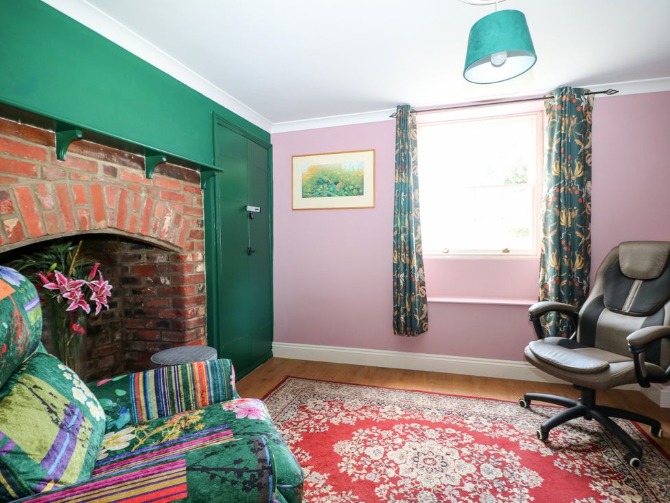 A sitting room with a fireplace and a chair at The Old School House in Selsey