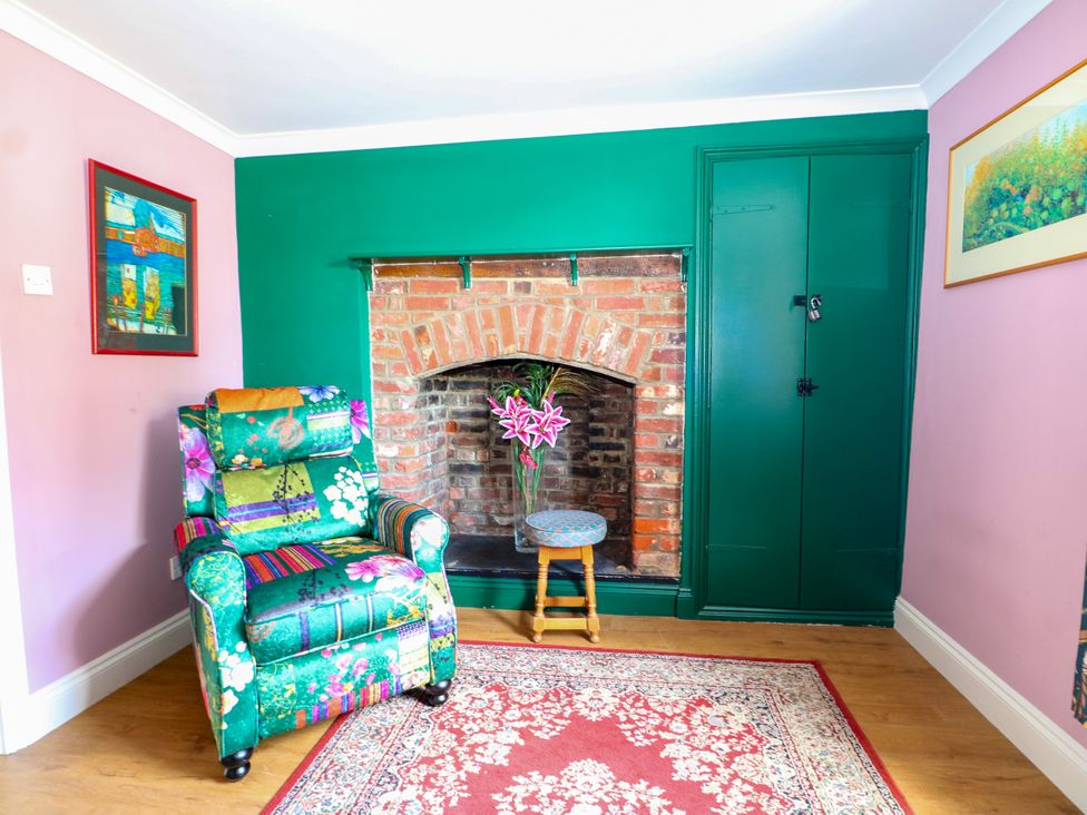 A living room with a floral armchair and fireplace at The Old School House in Selsey
