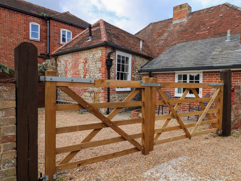 A wooden gate with gravel pathway and buildings at The Old School House in Selsey