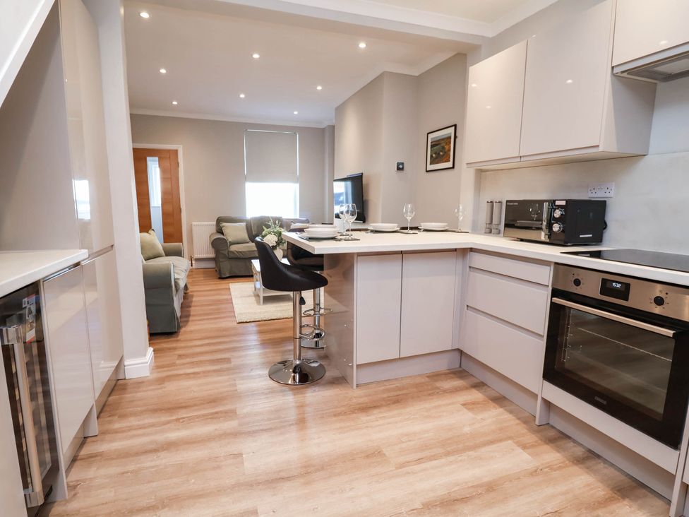A kitchen with bar stools and appliances at Brightside in Hoylake