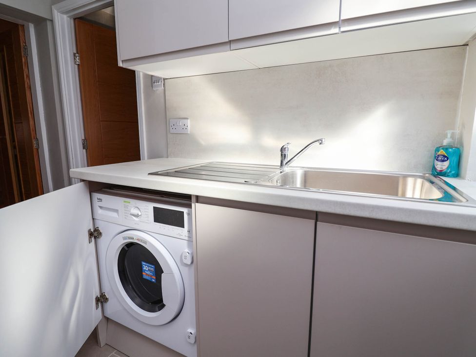 A laundry room with a washing machine and kitchen sink at Brightside in Hoylake