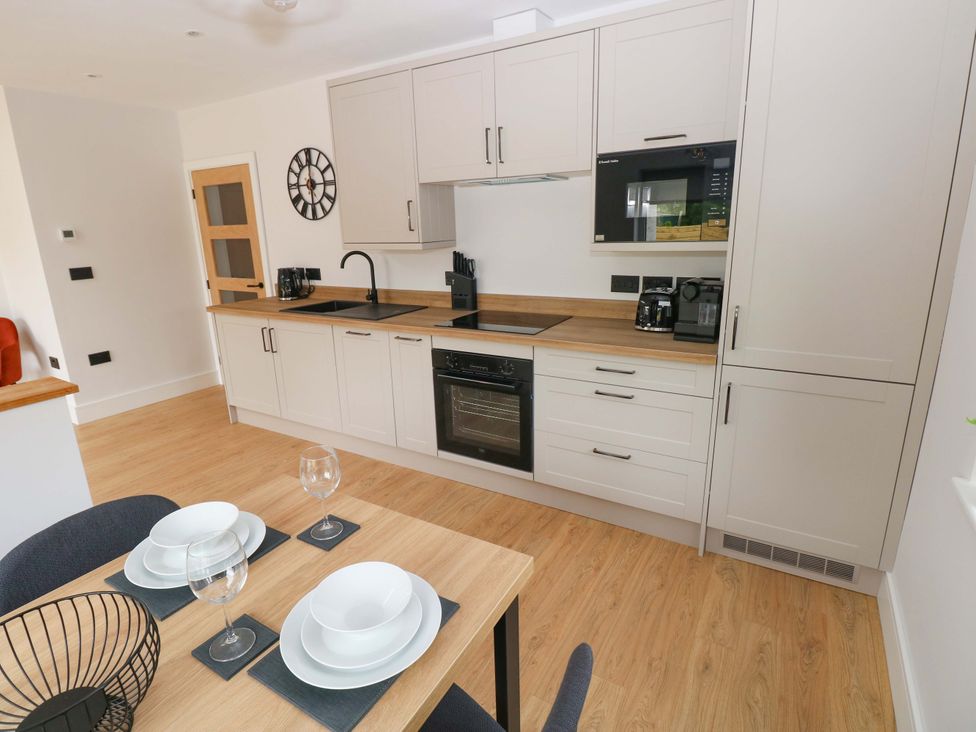 A kitchen with modern appliances and a dining table at Y Bwthyn Burry Port